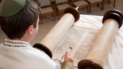 A young man reads the Torah.